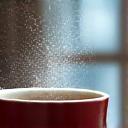 Manos acunando una taza de té caliente junto a una ventana empañada, sugiriendo confort y manejo de la rigidez invernal.