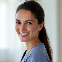 Retrato profesional de la Dra. Elena Durán, fisioterapeuta con experiencia, sonriendo amablemente en un entorno clínico limpio y moderno.